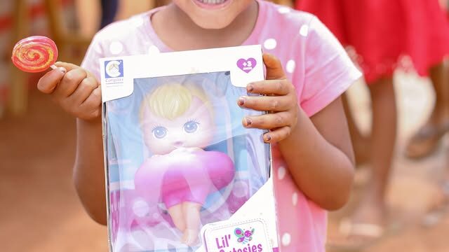 Criança segura uma boneca recebida