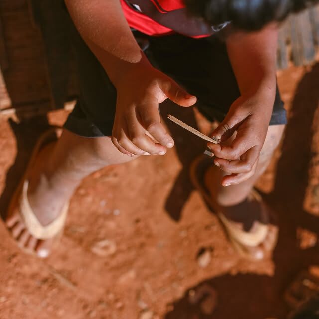 Menino fabrica um brinquedo com um pedaço de madeira